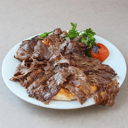 Grilled lamb slices served with roasted tomato, parsley, and flatbread