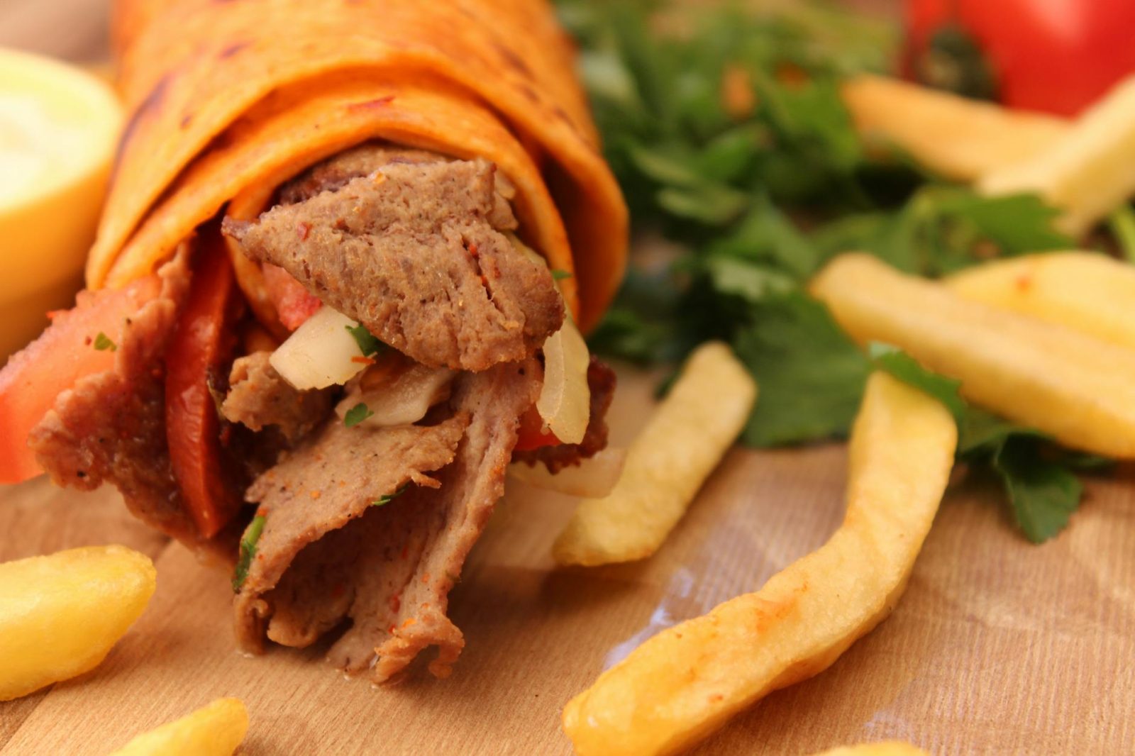 delicious doner kebab with fries on wooden table