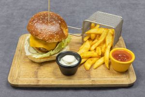 Cheeseburger with fries and dips on the side on a wooden tray
